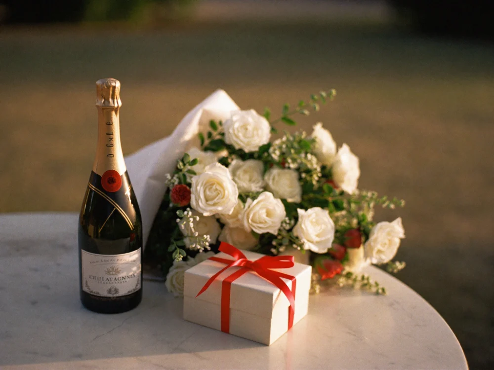 Champagne, roses and a gift on a marble table